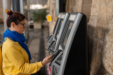Close-up of a woman paying at a self-service machine using a contactless phone payment