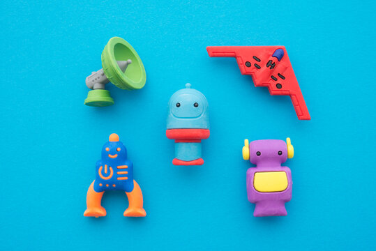 Flat lay of cute AI robots and advance technology eraser toy set on blue background minimal style. Kids imagination, learning, back to school and education concept.