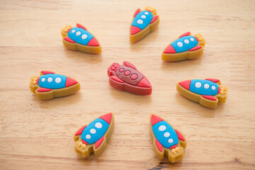 Leadership concept. Red rocket is leader in meeting among small blue rockets on wooden background....