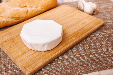Fototapeta na wymiar moldy cheese on a paper packaging. camembert in white paper packaging on the kitchen table