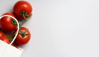 White paper bag with tomatoes on gray background, place for text,top view