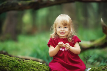 Little girl in the wild green forest