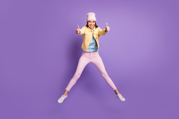 Fototapeta na wymiar Full length body size photo of young woman jumping showing like thumb-up sign both hands isolated on vibrant purple color background