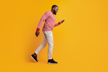 Profile portrait of man hold smartphone look screen walk on yellow background