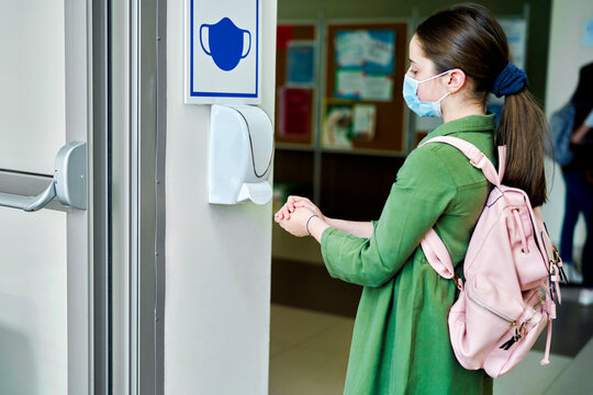 Schoolgirl wearing protective face masks disinfect their hands - Powered by Adobe