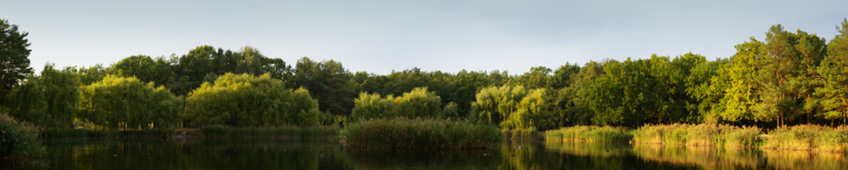 Panorama of city park and lake at evening light in Kyiv
