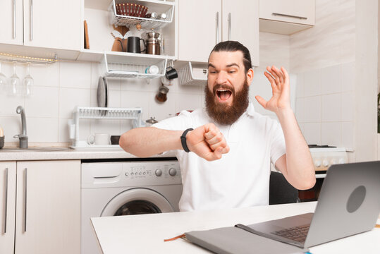 Oh No I Am Late For Work. Bearded Man Sitting In The Kitchen Is Looking At His Watch.