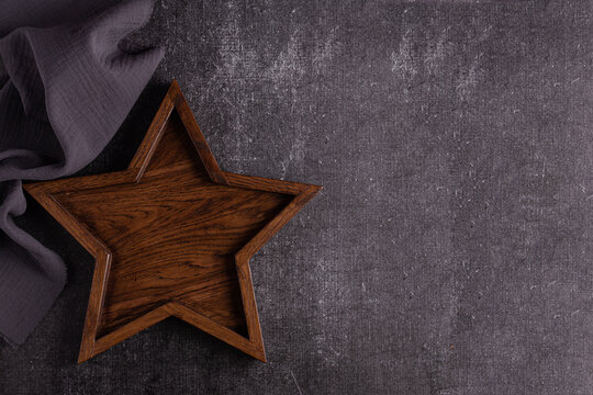 A large wooden tray in the shape of a star lies on a dark background.
