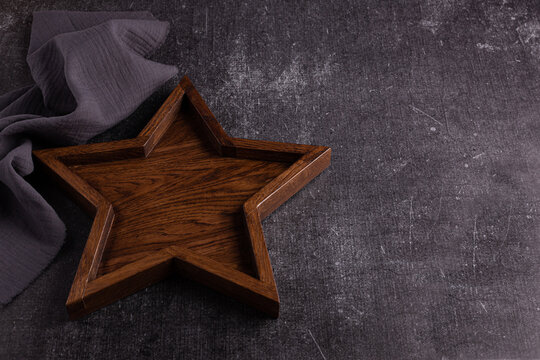 A large wooden tray in the shape of a star lies on a dark background.