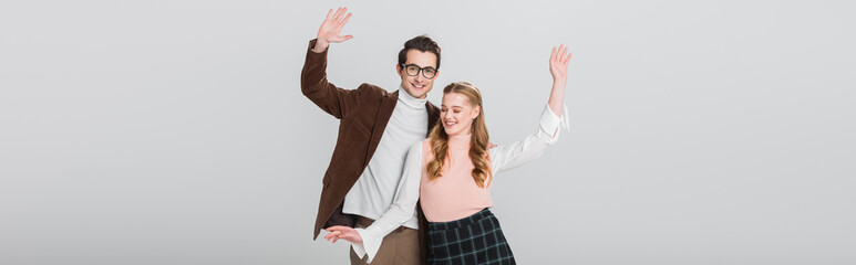 Fototapeta premium happy couple in vintage clothes dancing with raised hands isolated on grey, banner