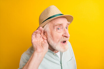 Photo of impressed pretty mature man dressed green shirt cap glasses arm ear listening secret...