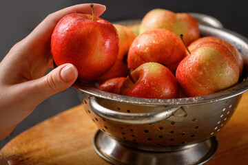 Human hand takes one apple from metallic bowl full of red ripe apples. Healthy eating. Apple pie ingridients. Cooking at home