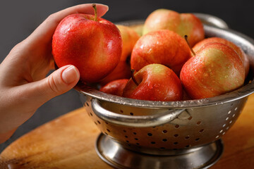 Human hand takes one apple from metallic bowl full of red ripe apples. Healthy eating. Apple pie...