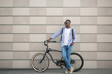 Urban lifestyle. Full length portrait of cool black guy with bicycle near brick wall outside, blank space