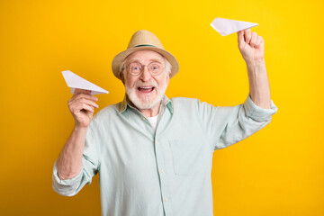 Photo of childish cute mature man dressed green shirt cap glasses smiling throwing paper planes...