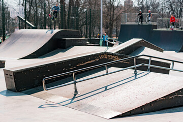 Multiple obstacles in outdoor skatepark in city's park. Shapes. Rails. Uphills. Downhills. Tricks....
