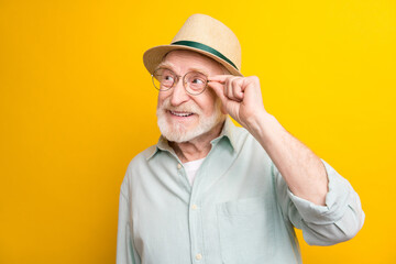 Photo of excited sweet age gentleman wear green shirt arm spectacles headwear looking empty space isolated yellow color background