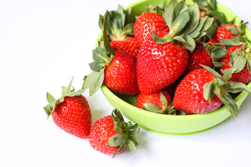 bright and tasty strawberries in a plate. green plate. side view. strawberries on white background