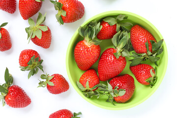 Delicious juicy strawberries in a children's green plate. Fresh strawberries in a plate and scattered near the plate. with copy space.