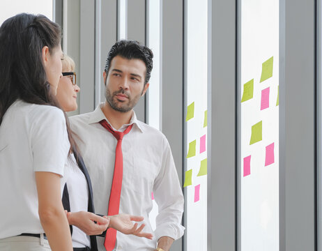 Diversity Business People Serious Discussion In Small Team Meeting On Sticky Notes At The Window Wall. Selective Focus.