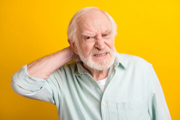 Photo of stressed unhappy mature man dressed green shirt arm neck feeling pain isolated yellow color background