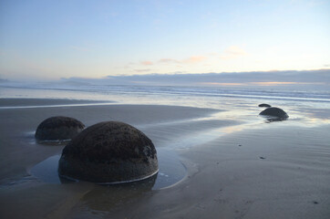 The Moeraki Boulders are unusually large and spherical boulders lying along a stretch of Koekohe Beach on the wave-cut Otago coast of New Zealand.