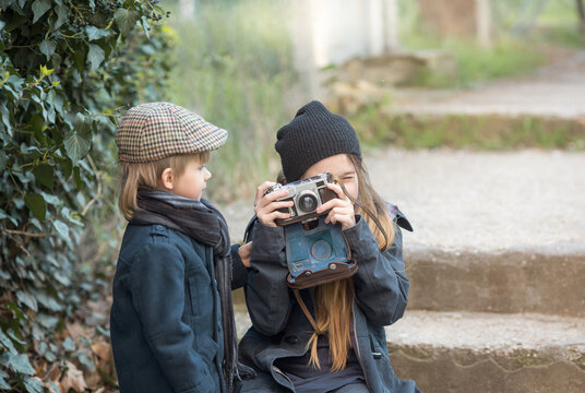 children boy and girl learn to take pictures. They are on a trip, dressed in fashionable vintage clothes