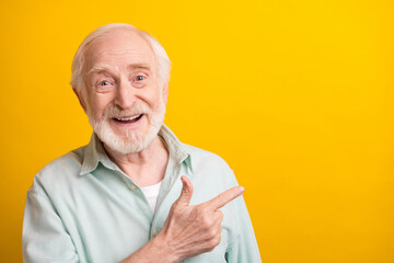 Photo of positive sweet age gentleman wear green shirt pointing finger empty space smiling isolated...
