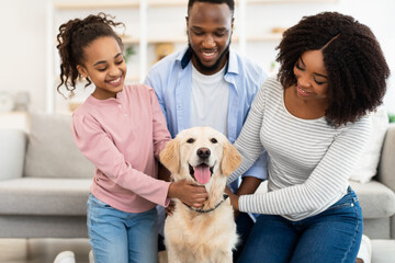 Young black couple hugging with dog posing at home