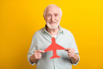 Photo of funny pretty mature man dressed green shirt holding red paper heart isolated yellow color...