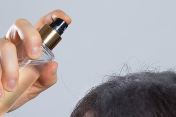 The woman puts on her hair a tonic of hydrolyte from a bottle. Hair care at home, dry dehydrated...
