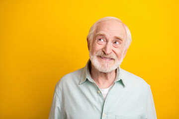 Photo of pretty positive mature man dressed green shirt smiling looking empty space isolated yellow color background