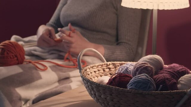 Young woman knitting at home in evening, closeup
