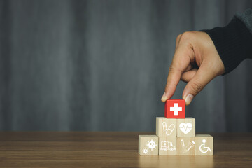 Hand holding red wood block of  plus sign on icon wooden arrangement. Healthcare and Medical concept. Insurance good heath. Patient beware virus. hospital treatment. Family Safety. Medicine protect.