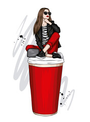 A beautiful girl in stylish clothes sits in a large glass of coffee. Fashion and style, clothing and accessories.