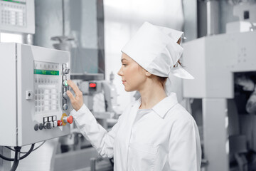 Conveyor switchboard concept. Factory engineer woman operating machine control panel in mill flour,...