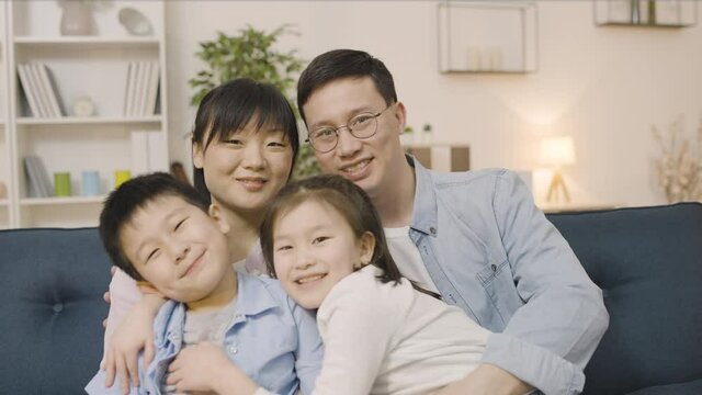 Portrait of happy asian family, parents and two kids smiling and hugging in cam