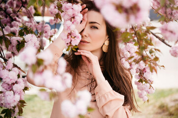 Fototapeta premium Girl in park under blossom sakura tree flowers