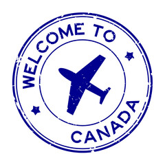 Grunge blue welcome to Canada word with airplane icon round rubber seal stamp on white background