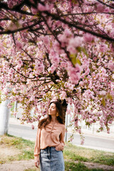 Girl in garden under blossom sakura tree flowers