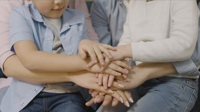 Happy parents and children stacking hands together, family support and care