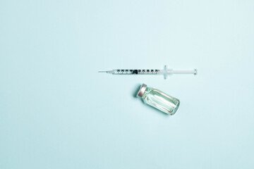 Syringe with medicine from glass vial on light blue background, flat lay, copyspace. Vaccination against influenza, covid 19, measles, coronavirus disease. Vaccination and immunization concept