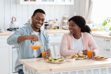Morning Meal. Cheerful Black Man And Woman Having Breakfast In Kitchen