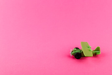 Small plastic airplane with copy space on pink background.