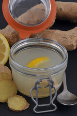 Infusion de gingembre et de citron frais dans un bocal en verre en gros plan sur fond noir