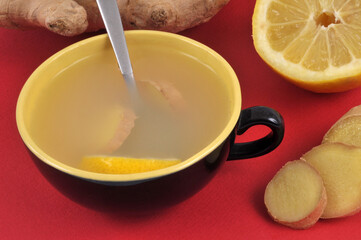 Infusion de gingembre et de citron frais dans une tasse en gros plan sur fond rouge