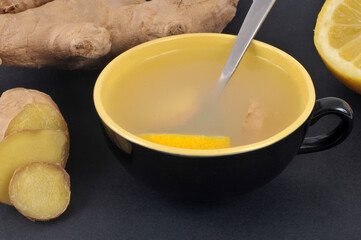 Infusion de gingembre et de citron frais dans une tasse en gros plan sur fond noir