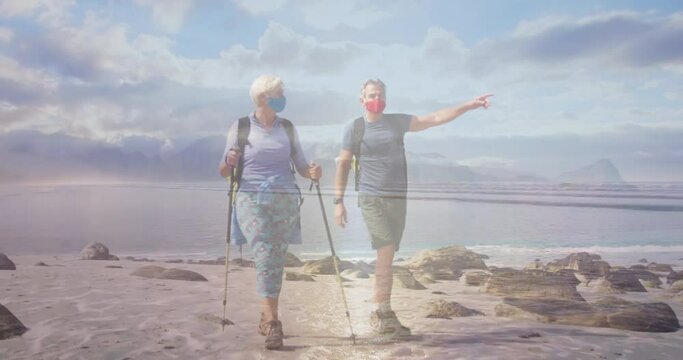 Caucasian Senior Couple In Face Masks Hiking On The Coast, Over Moving Sea