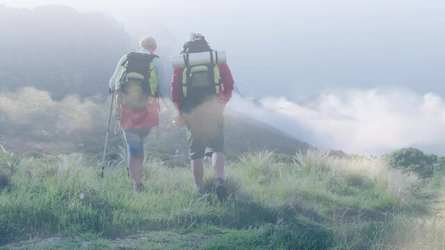 Happy caucasian senior couple hiking in mountains over fast moving clouds