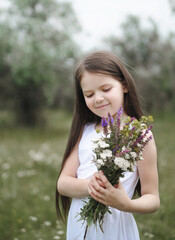 Fototapeta premium Little cute girl in white dress posing in the meadow.